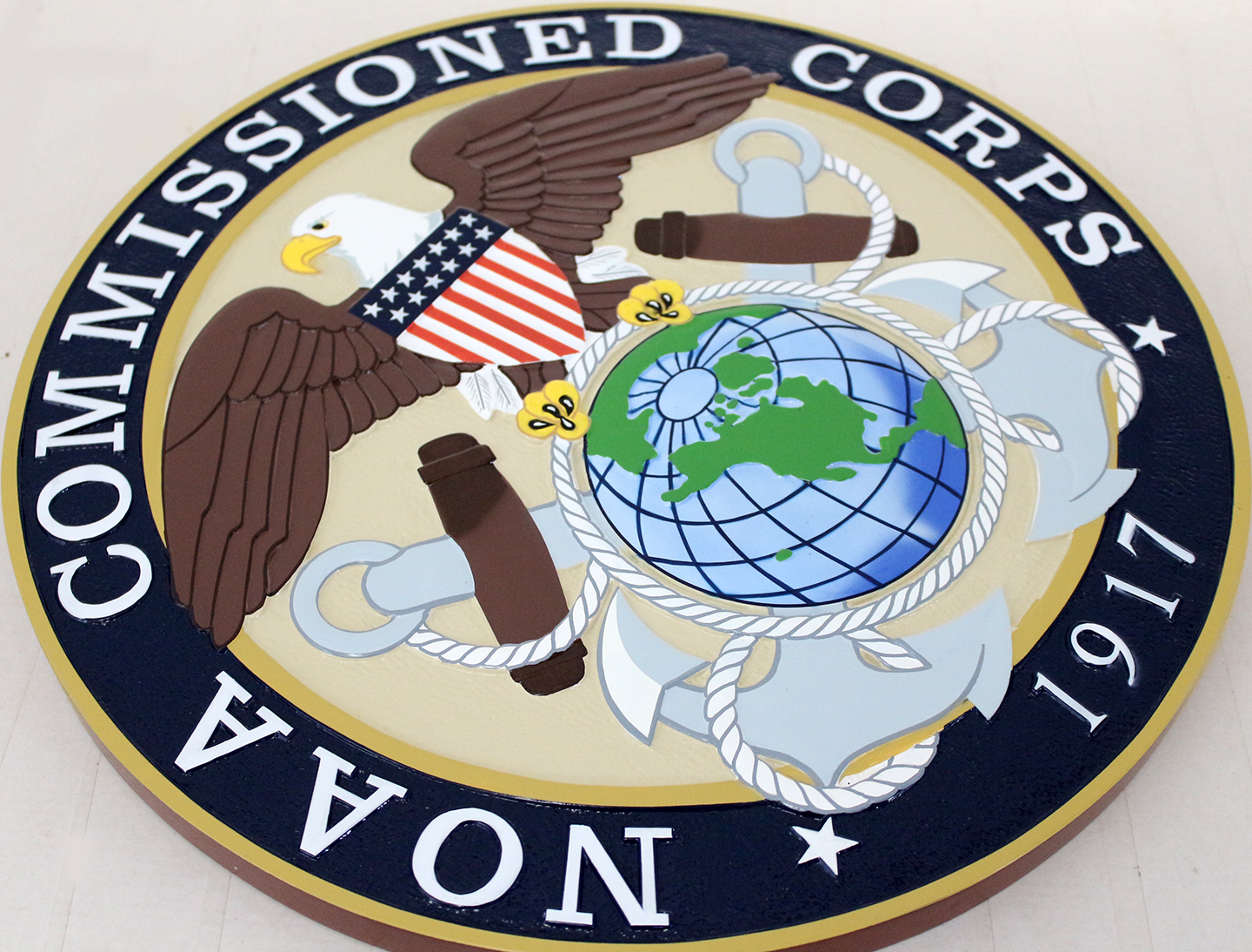 Angled view of the fully painted NOAA seal plaque showing raised eagle, globe and lettering details.