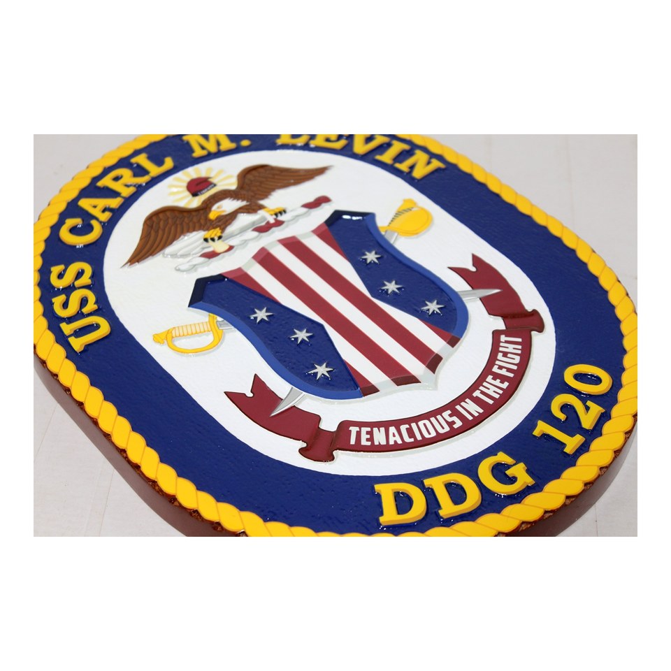 Angled view of a USS Carl M. Levin DDG-120 crest plaque with red, white and blue detail and a gold rope border.